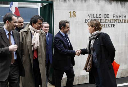 France's President Nicolas Sarkozy (C) shakes hands as he leaves a polling station with political advisor Pierre Lellouche (2nd L) and current local mayor Francois Lebel (C rear) in the first round local elections in Paris March 9, 2008.
