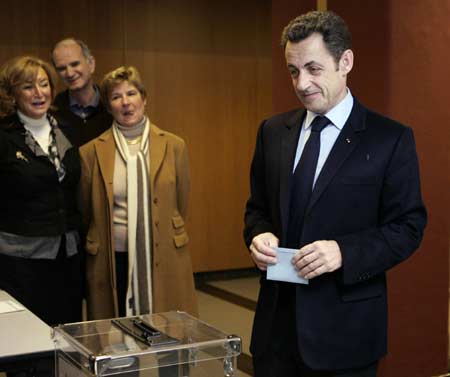 France's President Nicolas Sarkozy (R) waits to cast his ballot in the first round local elections in Paris March 9, 2008. Sarkozy's centre-right Union for a Popular Movement (UMP) party suffered losses in the first round of municipal elections in the country on Sunday.