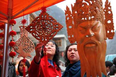 Tourists look at handicrafts during the 6th Guizhou (Anshun Longgong) Cole Flower Tour Festival, opened at the Longgong scenic area in Anshun City, southwest China's Guizhou Province, March 8, 2008. (Xinhua Photo)
