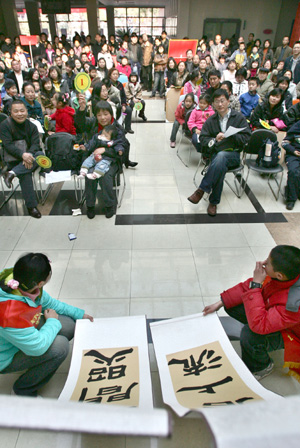 Child show their works for auction during a commonweal auction in Hangzhou City, capital of east China's Zhejiang Province, March 9, 2008. 60 painting works created by members of the Hangzhou youth painting and calligraphy academy were sold during a commonweal auction. All the income will be used to imburse poor students' art eduction after school. (Xinhua Photo)