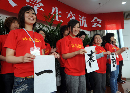 Japanese students display the Chinese characters meaning 'seperated by a narrow water' refering to the geographic neighborhood between China and Japan, during their visit in Hangzhou, capital of east China's Zhejiang province, on March 12, 2008. 