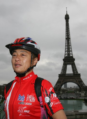 Yu Xudong, one of two Chinese riders on the tour, poses for a photo in front of the Eiffel Tower before the start of the cycling tour on Sunday, March 16, 2008. 