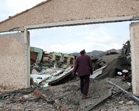 A man walk among destroyed houses in the village of Gerdec, Albania, Sunday, March 16, 2008. Troops and police cordoned off a smoldering army depot north of the Albanian capital as crews searched Sunday for workers missing following a chain of explosions Saturday that killed at least nine people and injured hundreds.