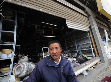 Photo taken on March 16, 2008 shows storekeeper Ma Menai and his store which was damaged during the March 14 unrest in Lhasa, capital of southwest China's Tibet Autonomous Region. (Xinhua Photo)