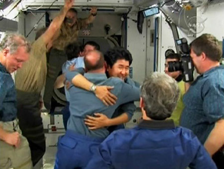 Garrett Reisman (L) hugs Takao Doi (R) after the farewell ceremony from aboard the International Space Station in this image from NASA TV March 24, 2008. The crews of the shuttle Endeavour and the ISS (L-R) Dominic Gorie, Rick Linnehan, Gregory Johnson, Leopold Eyeharts, Mike Foreman(with camera) and Yuri Malenchenko. Peggy Whitson and Robert Behnken hug each other in the background. 