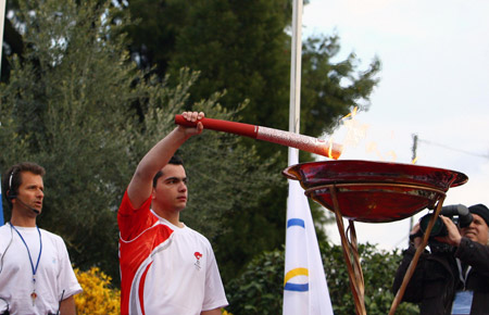 Torchbearer Yiogos from Ioanina kindles the Olympic flame basin with the torch during the second day of the torch relay of the Beijing Olympic Games in Ioanina of Greece on March 25, 2008. 