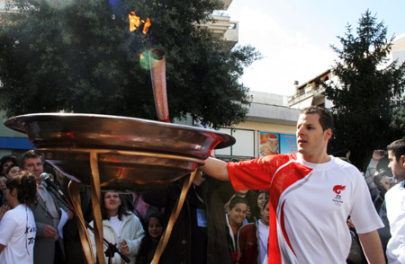 A torchbearer from Arta kindles the Olympic flame basin with the torch during the second day of the torch relay of the Beijing Olympic Games in Arta of Greece on March 25, 2008.
