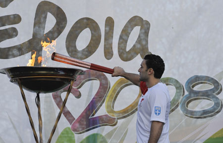 Torchbearer Dimitris kindles the Olympic flame basin with the torch at the end of the third-day torch relay of the Beijing Olympic Games, in Veria of Greece on March 26, 2008. 