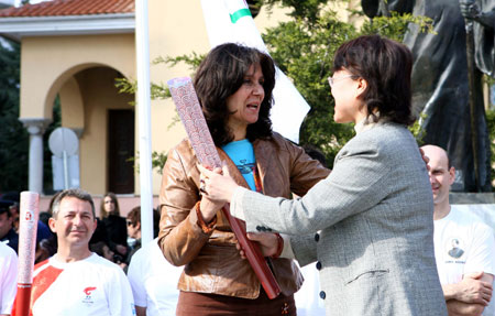 Liang Hui (R), representative of the Organizing Committee of the Beijing Olympic Games, presents a torch of the Games to the deputy mayor of Kozani during the third-day torch relay of the Beijing Olympic Games, in Kozani of Greece on March 26, 2008.