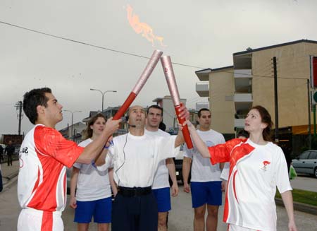 Torchbearer Toamios (1st R) from Ioanina kindles the torch of the next torchbearer on the third day of the torch relay of the Beijing Olympic Games, in Ioanina of Greece March 26, 2008. 