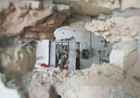 Residents stand at the door of their damaged house after clashes in Baghdad's Sadr City March 29, 2008.(Xinhua/Reuters Photo)