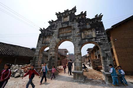 Children walks past a memorial gateway for dutiful sons and daughters at the architectural complex of the official residence of Cen Mi, a tusi (system of appointing national minority hereditary headmen in the Yuan, Ming and Qing dynasties) in Ming dynasty, at Nalao town, Xilin county, southwest China's Guangxi Zhuang Autonomous Region, March 31, 2008.