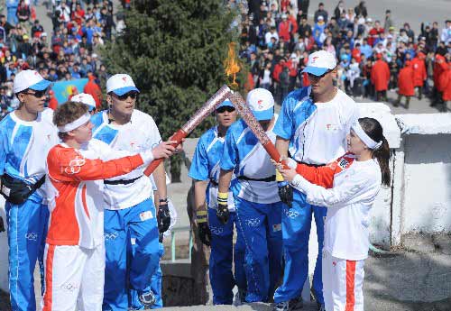The sixth Torch bearer Zhamilya Yunusbaeva(front R) ignites the torch from Kazakhstan swimmer Olegrabota at the Dam during the Olympic torch relay in Almaty, Kazakhstan, April 2, 2008.