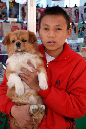 Luo Jie poses for a photo with his pet dog that came back to him some dozen days after lost in the March 14 Lhasa riots in Lhasa, capital of southwest China's Tibet Autonomous Region, on March 31, 2008. Luo Jie, a 14-year-old native Lhasa boy, told journalists on Sunday that the caption of a photo in a western website is totally wrong by saying he was arrested by Chinese police, the truth is that he was rescued by Chinese police after he was attacked by rioters on a street near Ramoqe Temple in the March 14 Lhasa riots. 