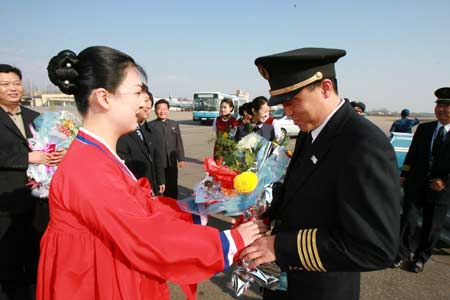 A Korean air hostess presents flowers to the captain of Air China's flight CA121 after the Boeing 737 plane landed at Sunan Airport, Pyongyang, capital of the Democratic People's Republic of Korea (DPRK), March 31, 2008. Air China launched its direct flight service from Beijing to Pyongyang on Monday. 