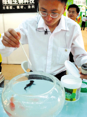 An exhibitor feeds a bowl of goldfish with his exhibit—toxin-free glue, to convince visitors that the new invention by his company is free of pollutants at the International Scientific Life Exhibition in Shenzhen on Sunday, April 6, 2008. 