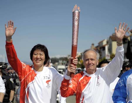 Torchbearer Lang Ping (L), now head of the U.S. women&apos;s volleyball team, and torchbearer James Dolan run with the torch in San Francisco, the United States, April 9, 2008. San Francisco is the sixth stop of the 2008 Beijing Olympic Games torch relay outside the Chinese mainland.