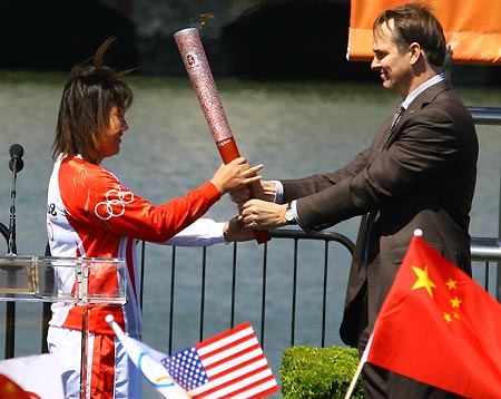 Norman Bellingham (R), chief Operating Officer of the United States Olympic Committee, gives the torch to torchbearer Lin Li at the McCovey Cove, the start of the Olympic torch relay in San Francisco, the United States, April 9, 2008. San Francisco is the sixth stop of the 2008 Beijing Olympic Games torch relay outside the Chinese mainland.