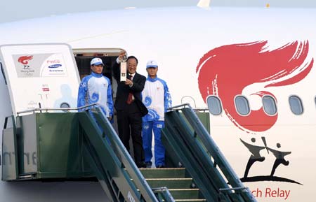 Liu Jingmin (C), the executive vice president of the Beijing Organizing Committee for the 2008 Olympic Games (BOCOG), walks out of the cabin with the lantern which holds the Olympic flame in his hands at the Ezeiza international airport, on the outskirts of Buenos Aires, the capital of Argentina, April 10, 2008. Buenos Aires is the seventh leg of the 2008 Beijing Olympic Games torch relay global tour outside the Chinese mainland. 