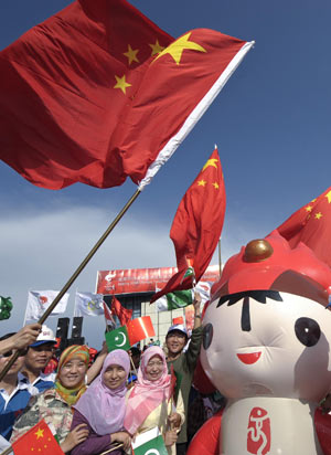 People pose for photos with one of the mascots of the 2008 Beijing Olympic Games during the Olympic torch relay at the Pakistan Sports Complex in Islamabad, capital of Pakistan, on April 16, 2008. 