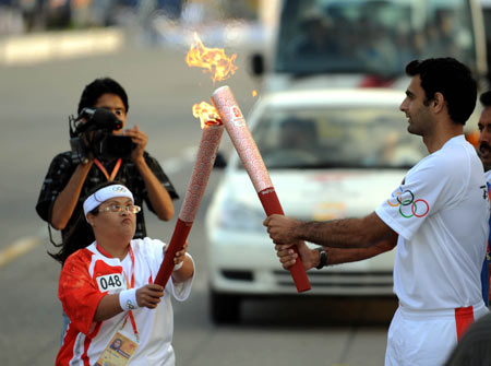 Torchbearer Seema Aziz (L) lights the torch for the next torchbearer Muhammad Shafiq during the 2008 Beijing Olympic Games torch realy in Islamabad, capital of Pakistan, on April 16, 2008.