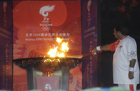 Torchbearer Hasan Sardar lights the cauldron with the torch during the 2008 Beijing Olympic Games torch realy in Islamabad, capital of Pakistan, on April 16, 2008.