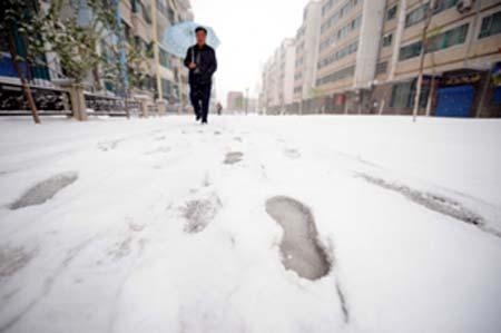 A resident walks in a snow covered street in Urumqi, capital of northwest China's Xinjiang Uygur Autonomous Region, on April 18, 2008.