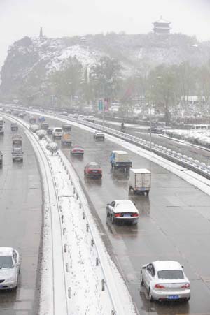 Cars move on the street as the snow-covered tree branches are seen in the foreground in the photo taken in Urumqi, capital of northwest China's Xinjiang Uygur Autonomous Region, on April 18, 2008.
