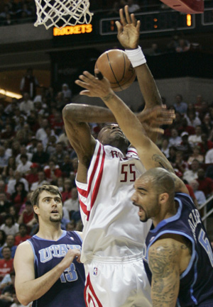 Utah Jazz forward Carlos Boozer (R) fouls Houston Rockets center Dikembe Mutombo as he goes up for a basket, as Jazz center Mehmet Okur watches, during the first half of Game 2 of their NBA basketball playoff series in Houston April 21, 2008. 