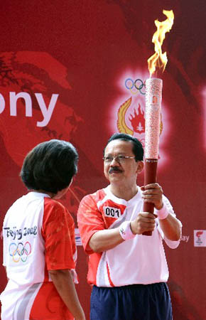 Rita Subowo (L), president of the National Olympic Committee of Indonesia, passed on the torch to Jakarta Governor Fauzi Bowo. 