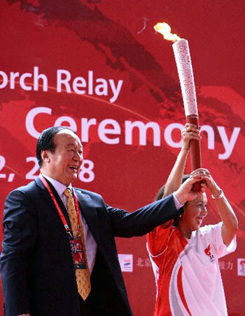 Jiang Xiaoyu (L), vice president of the Beijing Organizing Committee of Olympic Games (BOCOG), handed over the torch, which was kindled with the sacred Olympic flame from ancient Olympia of Greece, to Rita Subowo, president of the National Olympic Committee of Indonesia.