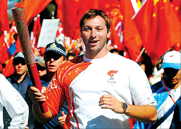 Legendary Australian swimmer Ian Thorpe carries the Olympic torch as thousands of people cheered on in Canberra yesterday. 