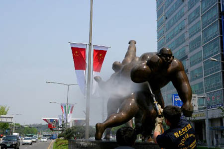 Workers in Seoul clean the Olympic Avenue Friday heralding the Beijing Olympic torch relay. The Seoul leg will start on April 27.