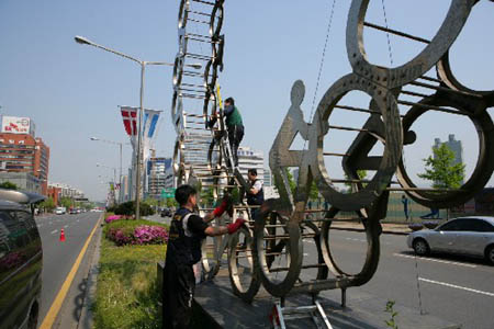 Workers in Seoul clean the Olympic Avenue Friday heralding the Beijing Olympic torch relay. The Seoul leg will start on April 27.