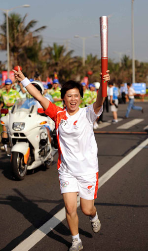 Torchbearer Wang Lifang runs with the torch during the 2008 Beijing Olympic Games torch relay in Haikou, south China's Hainan Province, on May 6, 2008. The Beijing Olympic torch relay in Haikou started at 8:10 a.m. on Tuesday at the Sea View Platform.