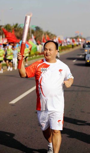Torchbearer Chen Wenbin runs with the torch during the 2008 Beijing Olympic Games torch relay in Haikou, south China's Hainan Province, on May 6, 2008. 