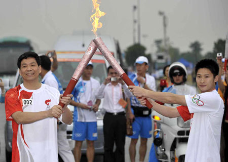 Torchbearer Yang Jinghui (R) lights the torch for the next torchbearer Liu Jiangnan during the 2008 Beijing Olympic Games torch relay in the southern Chinese city of Guangzhou Wednesday morning, May 7, 2008.