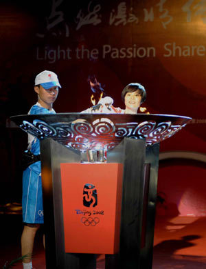 Torchbearer Wang Qihong (R) lights the cauldron with the torch during the 2008 Beijing Olympic Games torch relay in Shenzhen, south China's Guangdong Province, on May 8, 2008. 