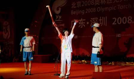 Torchbearer Wang Qihong (C) holds up the torch during a ceremony after the 2008 Beijing Olympic Games torch relay in Shenzhen, south China's Guangdong Province, on May 8, 2008. 