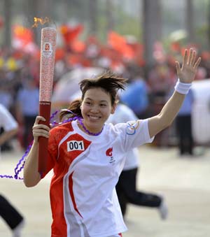 Torchbearer Chen Xiujun runs with the torch during the 2008 Beijing Olympic Games torch relay in Huizhou, south China's Guangdong Province, on May 9, 2008. 