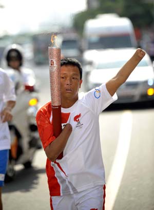 Torchbearer Chen Xishao runs with the torch during the 2008 Beijing Olympic Games torch relay in Huizhou, south China's Guangdong Province, on May 9, 2008.