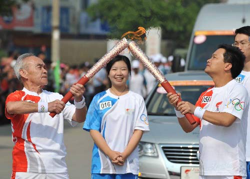 Photo: Torchbearer Chen Zhaoyang lights the torch for the next torchbearer Shi Xinfang