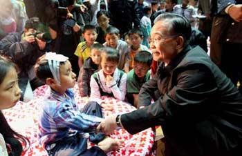 Chinese Premier Wen Jiabao comforts the wounded child in Mianyang on May 13, 2008. (Xinhua Photo)