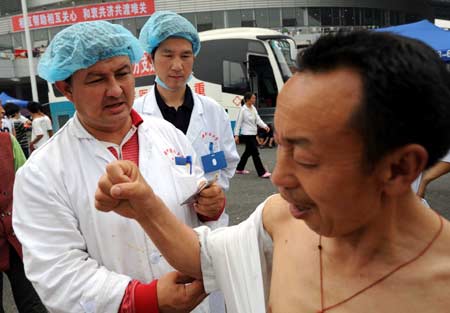 A doctor from northwest China's Xinjiang Uygur Autonomous Region treats a victim at the Jiuzhou Stadium in Mianyang City, southwest China's Sichuan Province, May 17, 2008. 