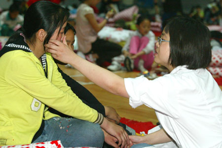 A psychologist consoles a girl who lost touch with her parents during Monday's earthquake in southwest China's Sichuan Province May 16, 2008. A renowned psychologist said Sunday in big disasters like southwest China earthquake, the country shall prepare long-term psychological counseling for victims, which might last for years.