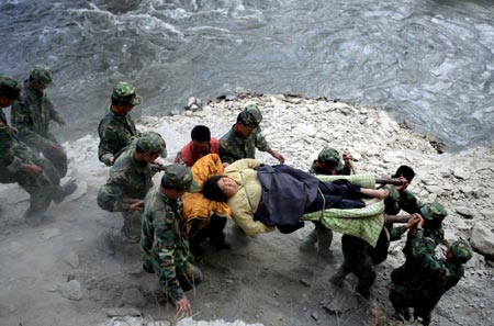 Soldiers carry an injured on a mountain road in the quake-hit Nanxin Town of Maoxian County, southwest China's Sichuan Province, May 18, 2008. 