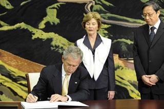 U.S. President George W. Bush (L) leaves words on the book of condolence as his wife Laura Bush (C) and Chinese Ambassador to the U.S. Zhou Wenzhong look on at the Chinese Embassy in Washington May 20, 2008. Bush came to the Chinese Embassy on May 20 to mourn Chinese quake victims.(Xinhua Photo)