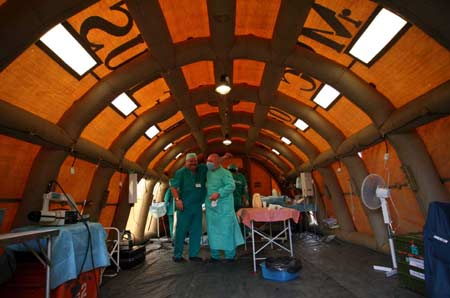 Two Russian surgeons pat each other self-congratulating on successfully winding up their second surgical operation at the quake-ravaged Pengzhou City，southwest China's Sichuan Province, May 21, 2008. The Russian medical team carried out surgical operations at the inflatable mobile hospital，comprising surgery rooms, patients’ward and other relevant facilities on Wednesday morning. 