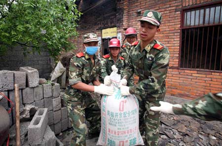 Frontier defense soldiers from south China's Guangdong Province carry grains out of a damaged house at Wuquan Village of Yonghe, a remote town in Anxian County, southwest China's Sichuan Province, on May 21, 2008. Guangdong frontier defense soldiers on Wednesday arrived in Yonghe and Jiepai, remote towns in Anxian County, to carry out rescue work including search for survivors, epidemic prevention and help residents in their reconstruction. 