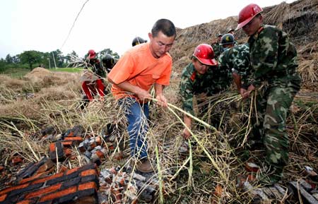 Frontier defense soldiers from south China's Guangdong Province help residents harvest cole at Wuquan Village in Yonghe, a remote town in Anxian County, southwest China's Sichuan Province, on May 21, 2008. Guangdong frontier defense soldiers on Wednesday arrived in Yonghe and Jiepai, remote towns in Anxian County, to carry out rescue work including search for survivors, epidemic prevention and help residents in their reconstruction. 